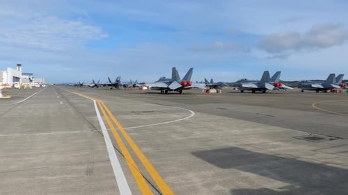 Lines of fighter jets sitting on the Naval runway, ready to deploy.