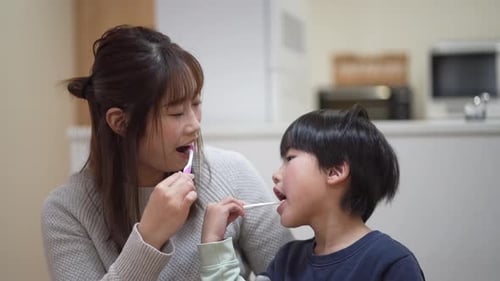 Woman and Child Brushing Teeth Together Indoors