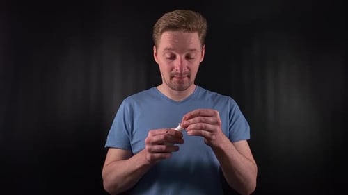 Un beau jeune homme utilise un spray nasal pour soulager l'écoulement nasal sur fond noir