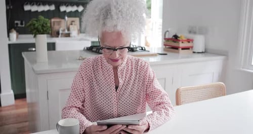 Senior Woman Using Tablet in Bright Kitchen