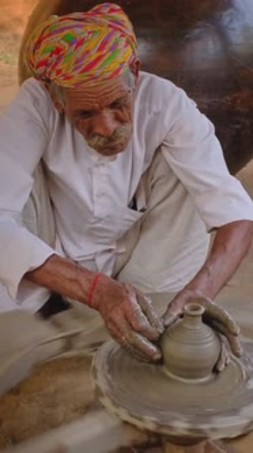 Potier indien au travail, lançant le tour de potier et façonnant des objets en argile, Rajasthan, Inde