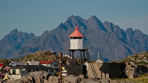 Coastal Village with Lighthouse and Mountain Backdrop