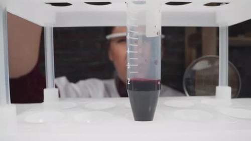 Scientist Examines Test Tube with Dark Red Liquid