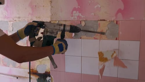 Empreiteiro remove ladrilhos cerâmicos do revestimento da parede Trabalhador fazendo desmontagem e demolição