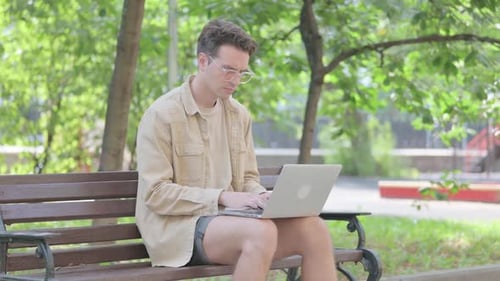 Man Works on Laptop in Sunny Urban Park