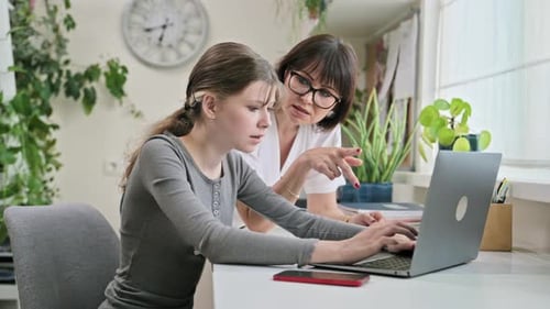 Teen and Adult Work Together on Laptop