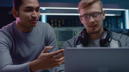 Der
Entwickler von Gaming-Software spricht mit einem IT-Ingenieur über das auf einem Laptop gezeigte Projektdesign. In der