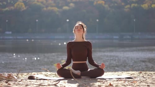Young Woman Meditating Outdoors on Sandy Beach