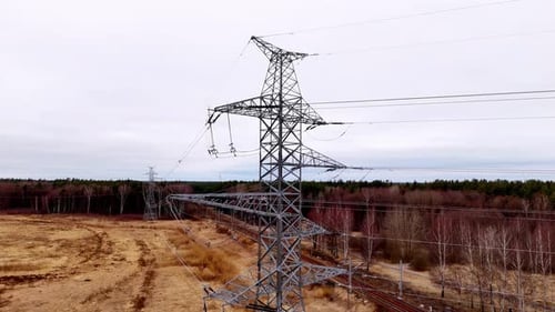 A tall power tower is seen in a field with a cloudy sky in the background. Concept of power and ener