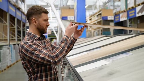 A Man Choosing Wood Laminated Flooring in Shop