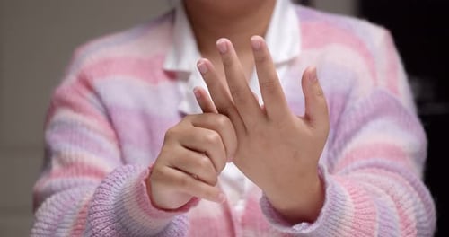 Nahaufnahme einer Person, die nacheinander ihre Finger kneift und sich massiert, um den Schmerz noch einmal zu erleben und