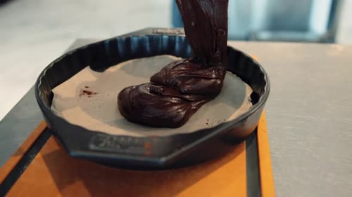 Die Schokolade wird in ein Blech gegossen, das bereit ist, in den Ofen gestellt zu werden. Dies markiert den Beginn der Browni