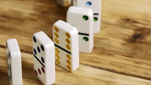 Dominoes Toppling in a Chain Reaction on a Wooden Table Surface