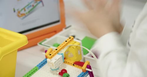 Caucasian Elementary School Boy in Glasses is Concentrating Assembling His Own Simple Model of Toy