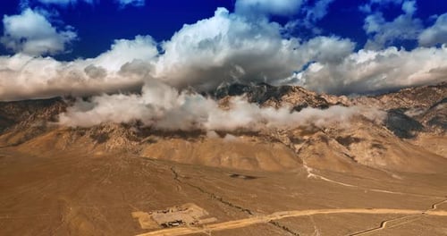 White clouds coating the mountains of Nevada on sunny day. Enormous cloudscape sliding by the rocks