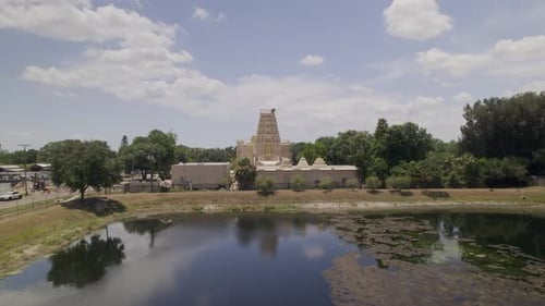 Drone survole un petit étang et survole un temple hindou surmonté d'un grand nid d'aigle.