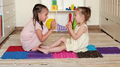 Girls Clapping Hands Together on Play Mats Indoors