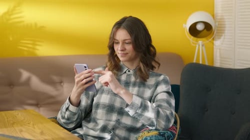 Woman Smiles Using Smartphone Indoors