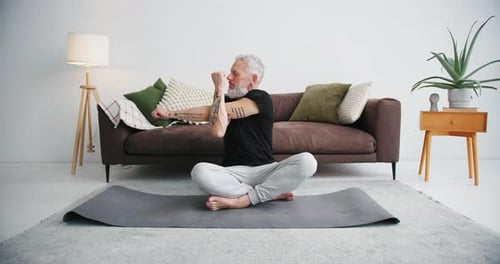 Mature Man Stretching on Yoga Mat Indoors
