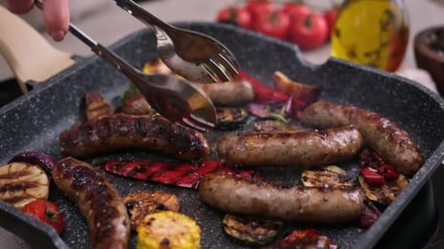 Homemade Juicy Pork Sausages with Spices and Vegetables Frying on Grill Frying Pan