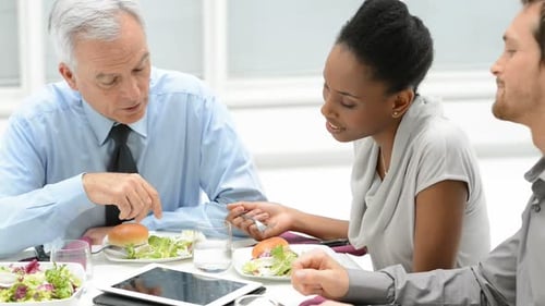 Colleagues Having Business Lunch Discussing Data on Tablet