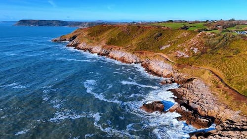 Waves crash against rocky cliffs along the coast.