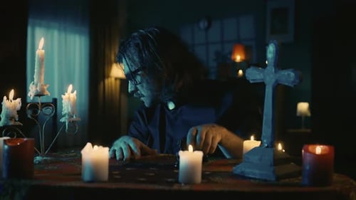 Man Reads Book Surrounded by Candles and Cross