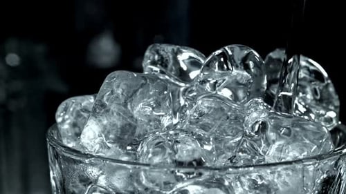 Water Pouring Over Ice Cubes in Glass