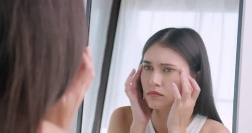 Concerned Woman Looks at Face in Mirror