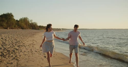 Young Loving Couple Have Fun Running on the Beach at Sunset