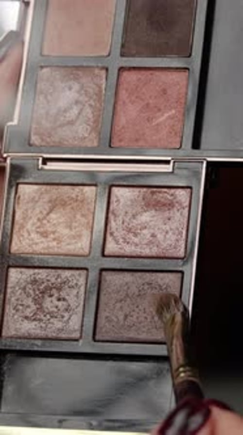 Professional Makeup Artist Swatches Eyeshadows on a Palette with a Brush Testing Different Shades of