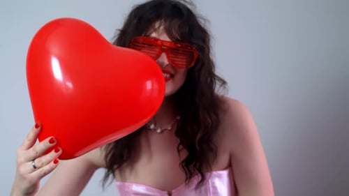 Playful Woman Poses with Red Heart Balloon