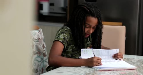 Teenage Girl Studying and Writing in Notebook at Home