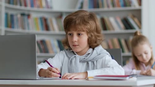 Boy Using Laptop to Learn in Library