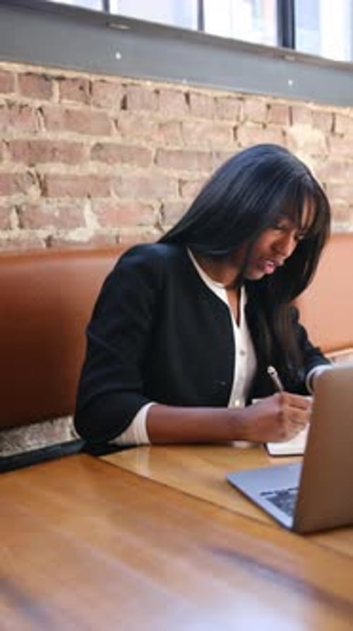African American Businesswoman Working on Laptop and Taking Notes