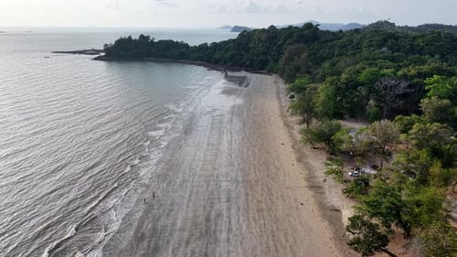 Aerial view captures calm ocean waves lapping sandy shore
