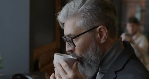 Closeup of Mature Businessman Drinking Coffee Relaxing in Cafe During Lunch Break