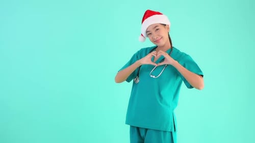 Female Doctor with Christmas Hat making Heart Sign. Copy Space SLOMO