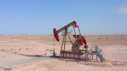 Drone Footage of Oil Pump Jack Painted Red Operating in Desert