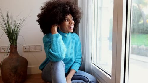 linda mulher afro-americana em casa feliz sentada perto da janela