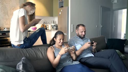 Family Using Mobile Phones at Home on Sofa