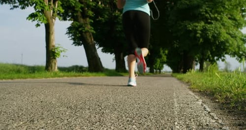 in a sunny spring day, a young girl goes to run under a tree-lined avenue to keep fit and for the