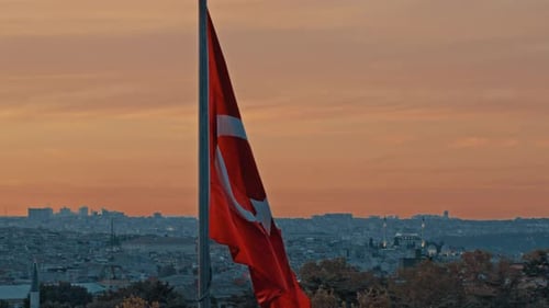 Flag Waving over City Skyline at Sunset