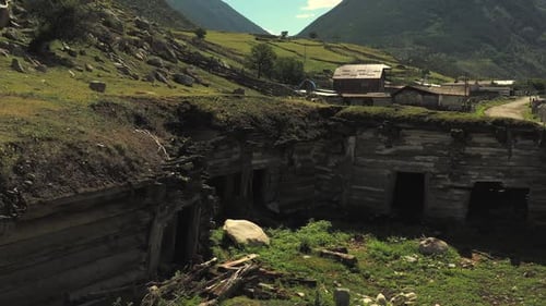 Aerial View of Abandoned Earth House Amidst Mountains and Village in the Caucasus
