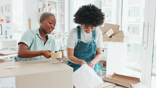 Women Packaging Boxes in Modern Office Space