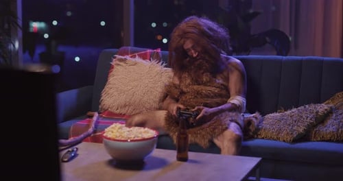 Sleepy and Funny Homo Sapiens Prehistoric Ancient Savage Wildman Human Sitting on Cocuh Watching TV