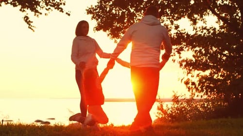Loving Family Walks in the Countryside During Sunset Mom and Dad Hug and Play with Their Son and