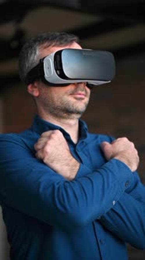Man gesturing while using a Virtual Reality headset in an office. Vertical