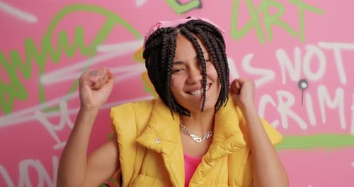 Excited woman dances against colorful graffiti background