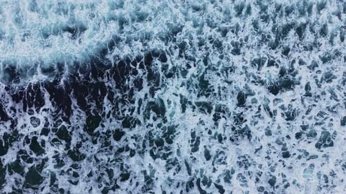 Waves crash against shore with foam and water at ocean surface